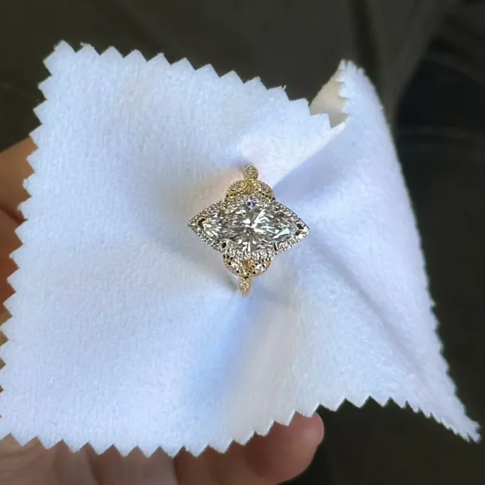 Marquise-cut diamond engagement ring with halo and gold band photographed on a white polishing cloth. Closeup highlights vintage details and sparkling facets.