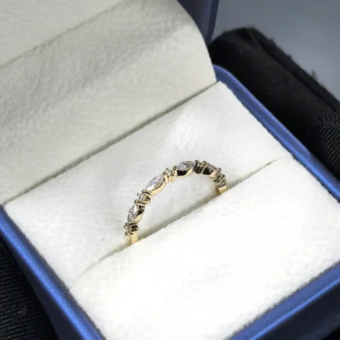 Elegant gold band with alternating round and baguette diamonds displayed in a plush navy box - delicate vintage stackable wedding or anniversary ring.